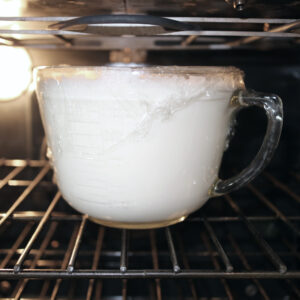 Homemade yogurt fermenting in oven with oven light on.